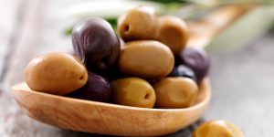 aceitunas arrugadas verdes y moradas en una cuchara de madera