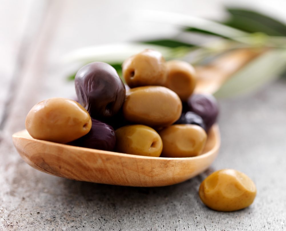 aceitunas arrugadas verdes y moradas en una cuchara de madera